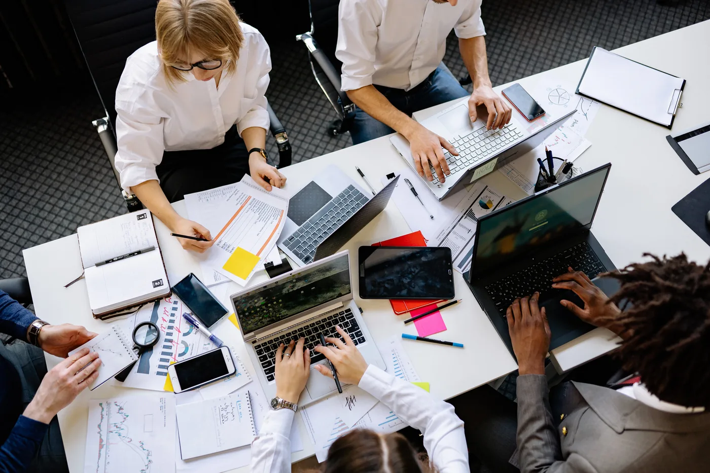 Overhead view of a team planning marketing work around a table with laptops